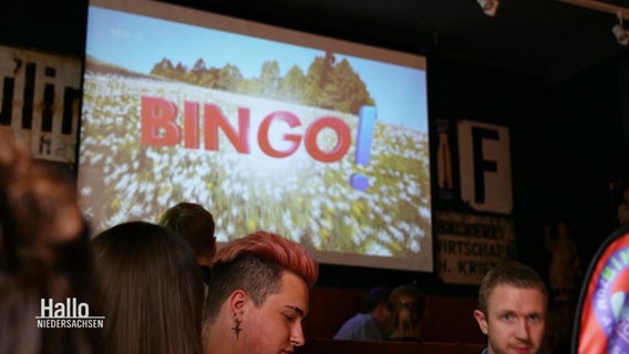 Eine Leinwand in der Dorfkneipe "Zum Amtsschimmel" auf dem BINGO! übertragen wird. © Screenshot 