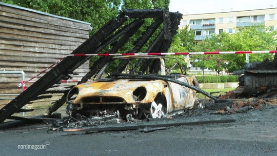 Ein ausgebranntes Auto und Carport. © Screenshot 