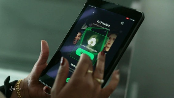 Hände mit dunkelrotem Nagellack auf den Fingern tippen auf einem Smartphone, auf dessen Bildschrim Gesichter sowie ein grünes Logo zu sehen sind. © Screenshot 