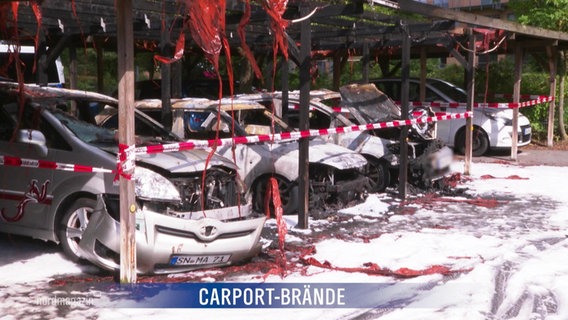 Ausgebrannte Autos stehen unter einem Carport. © Screenshot 
