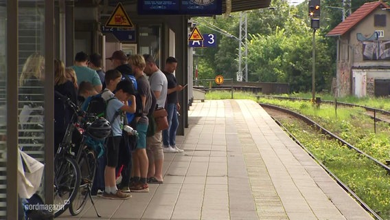 Wartende Menschen stehen auf einem Bahnsteig. © Screenshot 