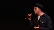 Max Mutzke, in schwarz gekleidet, singt. © Screenshot 
