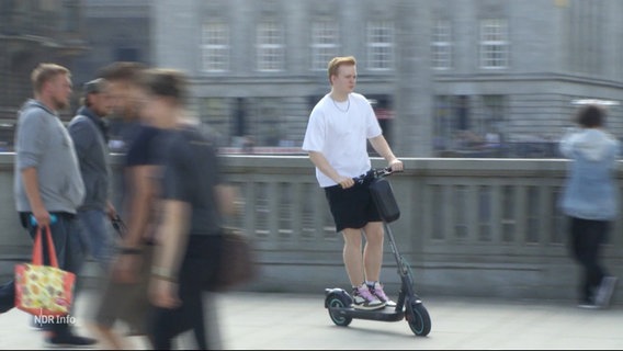 Ein junger Mann fährt auf einem E-Scooter. © Screenshot 