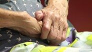 Die übereinender gefalteten Hände einer Seniorin. © Screenshot 