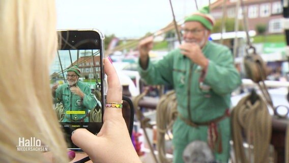 Eine Person macht ein Foto mit einem Smartphon auf einem Segelschiff. © Screenshot 