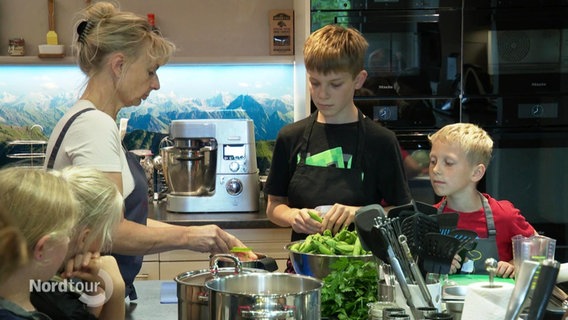 Kochlehrerin und Kinder bei einem Kochkurs. © Screenshot 