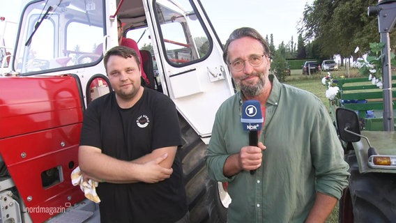 Ein Reporter und sein Interviewpartner neben einem Oldtimer-Traktor. © Screenshot 