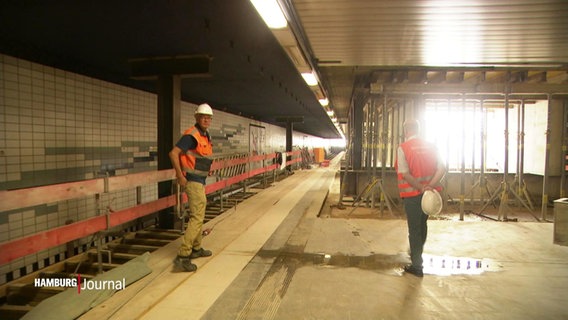 Zwei Männer in Warnwesten gehen durch die alte U-Bahnstation Horner Rennbahn. © Screenshot 