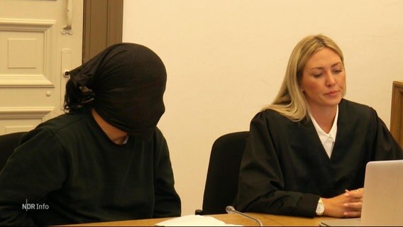 Der Angeklagte mit schwarzer Strumpfmaske im Gerichtssaal. © Screenshot 