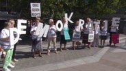 Ältere Damen halten die Buchstaben des Wortes "Demokratie" hoch, dazu ein Schilder mit der Aufschrift "OMAS GEGEN RECHTS". © Screenshot 