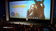 Die Leinwand und einige Reihen eines vollbesetzen Kinos bei der Premiere von "Ponyherz". © Screenshot 