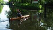 Ein Mann paddelt auf einem kleinen Fluss. © Screenshot 