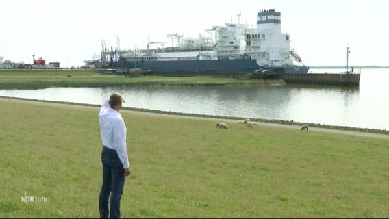 Ein Mann steht am Ufer und schaut zu einem LNG-Schiff. © Screenshot 