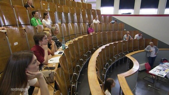 Mehrere Menschen sitzen auf den Stühlen eines Vorlesungssaals. © Screenshot 