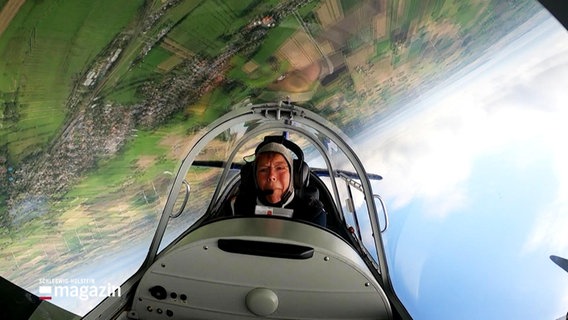 Kathi Suthau im Cockpit eines Flugzeugs, im Hintergrund stehen Himmel und Erde auf dem Kopf © Screenshot 