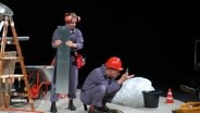Zwei als Bauarbeiter verkleidete Schauspielende auf einer Bühne. © Screenshot 