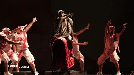 Ein Musiker von Deichkind und Tänzerinnen und Tänzer auf der Bühne. © Screenshot 