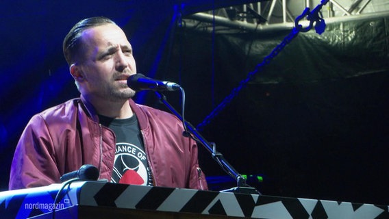 Der Rapper Danger Dan sitzt auf einer Bühne am E-Piano. © Screenshot 