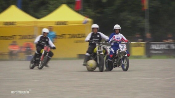 Bei einem Motoball-Spiel fahren drei Männer auf Motorrädern einem großen Ball hinterher. © Screenshot 
