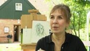 Carolin Beyer vor einer Zeichnung. © Screenshot 