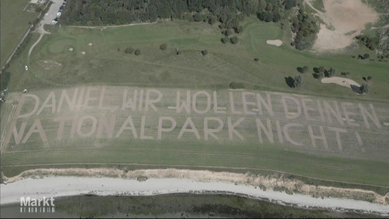 Eine Golfplatzwiese aus der Vogelperspektive, auf der steht: Daniel wir wollen deinen Nationalpark nicht. © Screenshot 