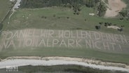 Eine Golfplatzwiese aus der Vogelperspektive, auf der steht: Daniel wir wollen deinen Nationalpark nicht. © Screenshot 