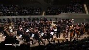 Ein Orchester auf der Bühne der Elbphilharmonie. © Screenshot 