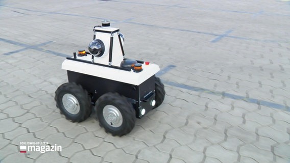 Ein Roboter mit vier Rollen auf einer Asphaltfläche. © Screenshot 