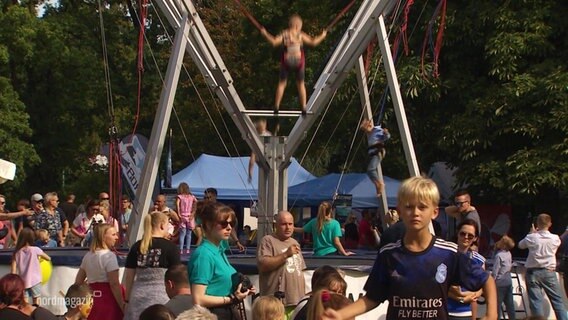 Auf einem Fest springen Kinder auf einem Bungee-Sprunggerät. © Screenshot 