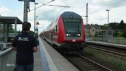 Eine Person auf einem Bahnsteig während eine Zug einfährt. © Screenshot 