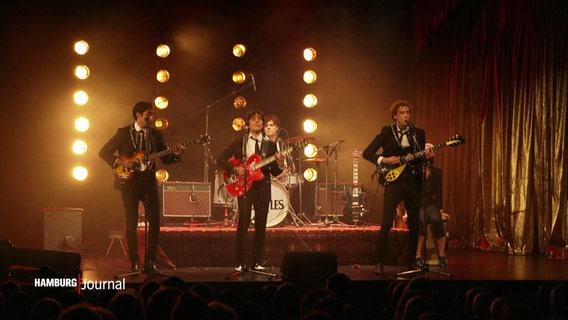 Blick auf eine Bühne. Vier junge Männer stellen die Beatles in ihren Anfängen nach. © Screenshot 