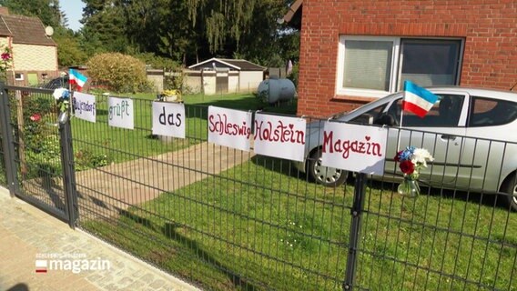 An einem Zaun wurde eine Willkommens-Botschaft für das Schleswig-Holstein Magazin geklebt. © Screenshot 