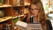 Ein Mädchen liest ein Buch in einem Buchladen. © Screenshot 