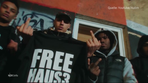 Ein Jugendlicher hält ein T-shirt mit der Aufschrift "Free Haus3" in den Händen. © Screenshot 
