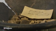 Eine 3.500 Jahre alte Urne mit einem Zettel in Nahaufnahme © Screenshot 