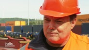 Ein Mann in Warnjacke und Helm in der Farbe Orange. © Screenshot 