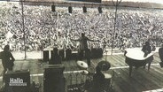 Ein Schwarz-Weiß-Bild von 1973 zeigt eine Band auf der Bühne des Musikfestivals in Scheeßel. © Screenshot 