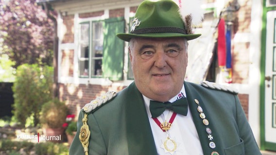 Ein Mann in grüner Uniformjacke und Hut © Screenshot 