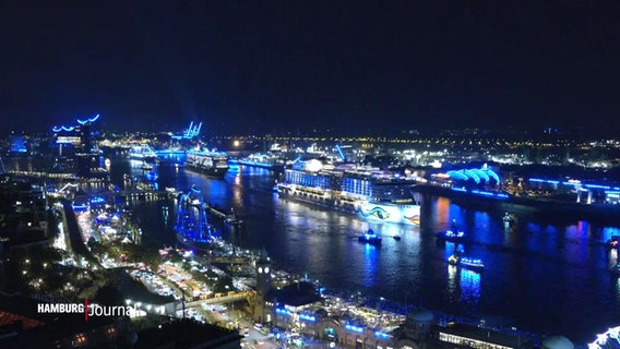 Ein Kreuzfahrtschiff fährt im blau beleuchteten Hamburger Hafen auf der Elbe © Screenshot 