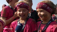 Zwei Kinder mit Stirnbändern und schlammverschmierten Gesichtern werden interviewt © Screenshot 
