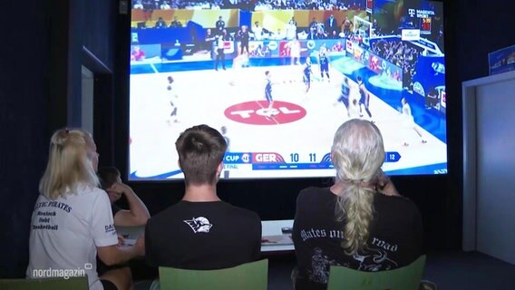 Drei Menschen schauen sich das Basketballspiel an. © Screenshot 