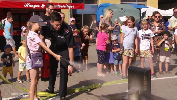 Ein Mädchen löscht einen kleinen Brand am Tag der offenen Tür bei der Feuerwehr. © Screenshot 