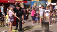 Ein Mädchen löscht einen kleinen Brand am Tag der offenen Tür bei der Feuerwehr. © Screenshot 