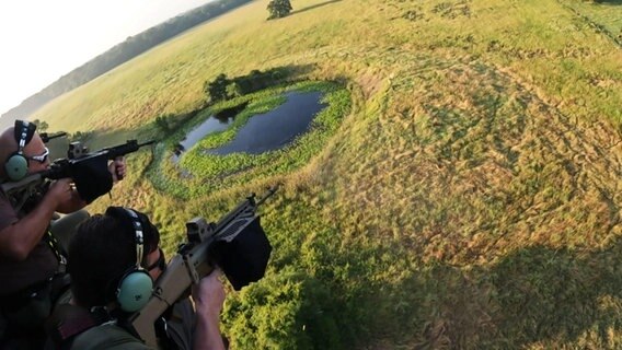 Zwei Männer schießen aus einem Helikopter auf ein Wildschwein. © Screenshot 