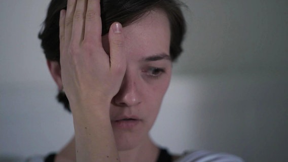 Eine Frau hält sich eine Hand vor ihr Auge. © Screenshot 