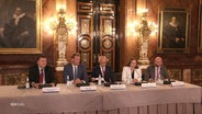 Ein Tisch mit dem Hamburger Bürgermeister, Senatoren und weiteren Personen im Rathaus. © Screenshot 