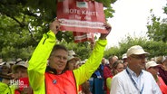 Protestierende, u.a. mit einem Schild: "Rote Karte für die Gesundheitspolitik". © Screenshot 