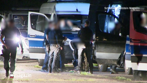 Vier Polizeibeamte stehen versammelt vor einem Wagen. © Screenshot 