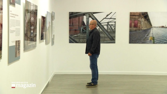 Weitaufnahme: Mann betrachtet ein Ausstellungswerk in einer Fotoausstellung. © Screenshot 