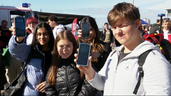 Schüler halten ihre Handy mit den Probewarnungen Richtung Kamera. © Screenshot 